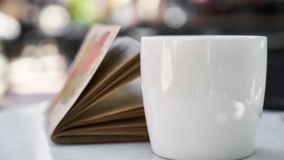 Coffee cup and journal on white table