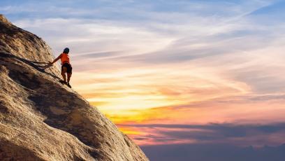 A woman climbing a mountain at sunset