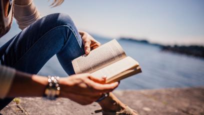 Woman reading a book by the lake