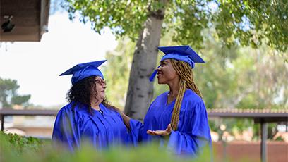 two female graduates smiling at each other during a commencement ceremony