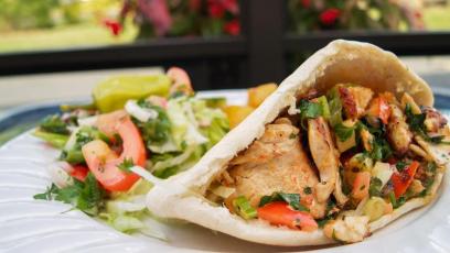 A chicken pita sandwich garnished with vegetables