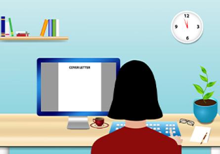 The woman is sitting at a desk and writes the cover letter on PC monitor in front of her