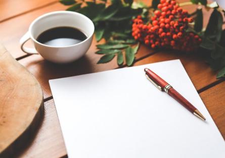 A blank journal, a cup of espresso, and red flowers